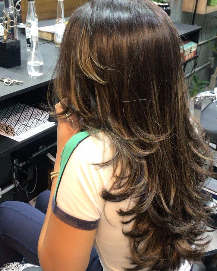 Long dark brown hair with layered, curled ends shown from behind in a salon