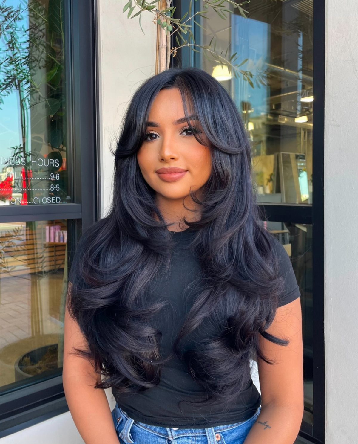 Woman showing long layered dark hair with voluminous ends and curtain bangs