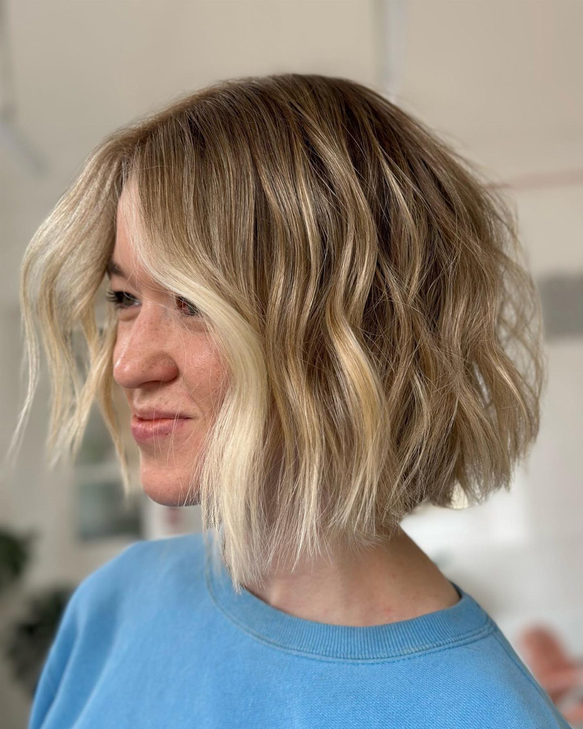 Woman with a wavy blonde lob and textured ends, shown in profile