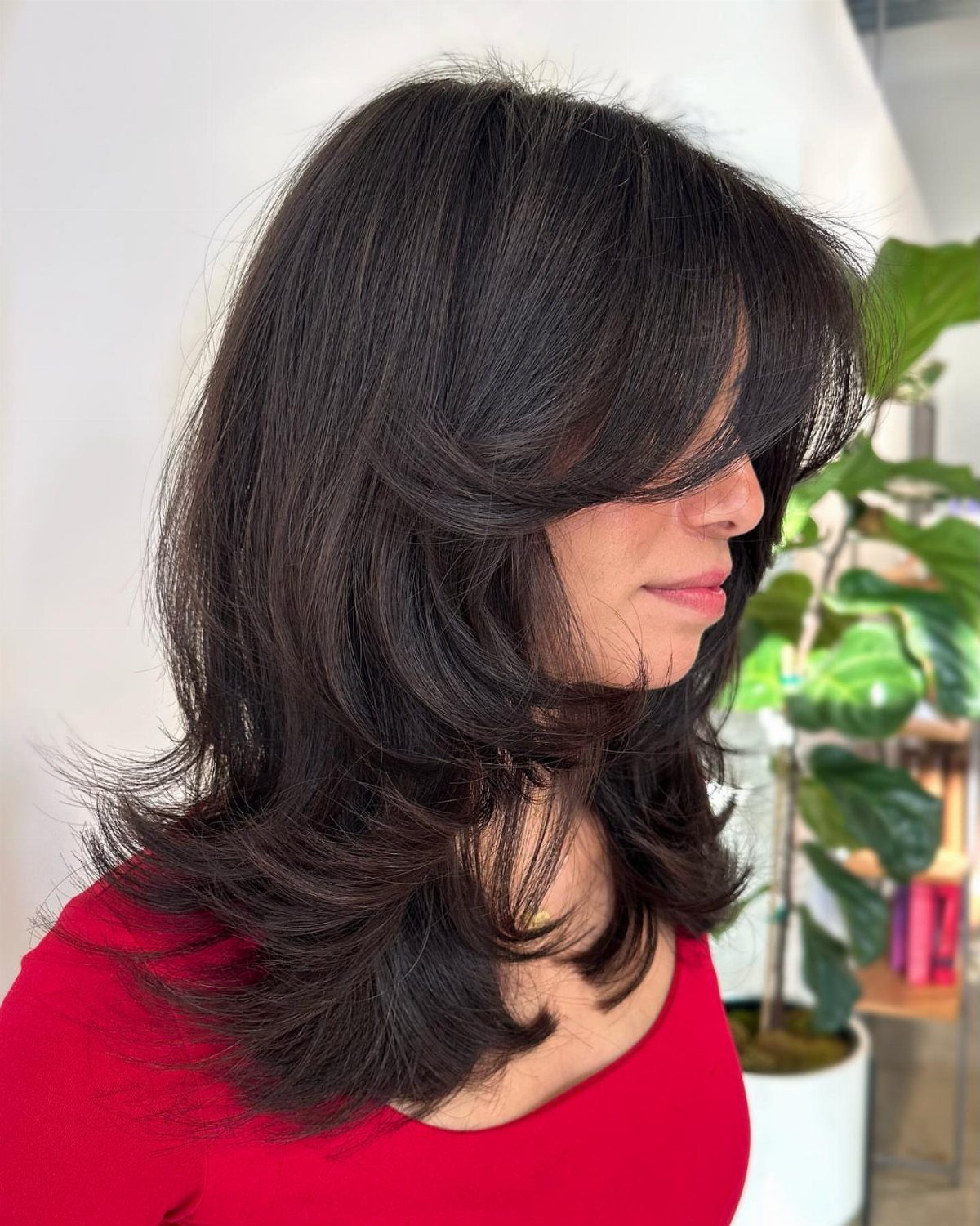 Woman showing a dark layered mid-length haircut with long side-swept bangs