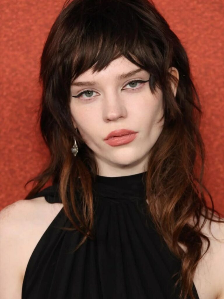 Woman with long, shaggy dark brown hair, choppy bangs, and layered waves