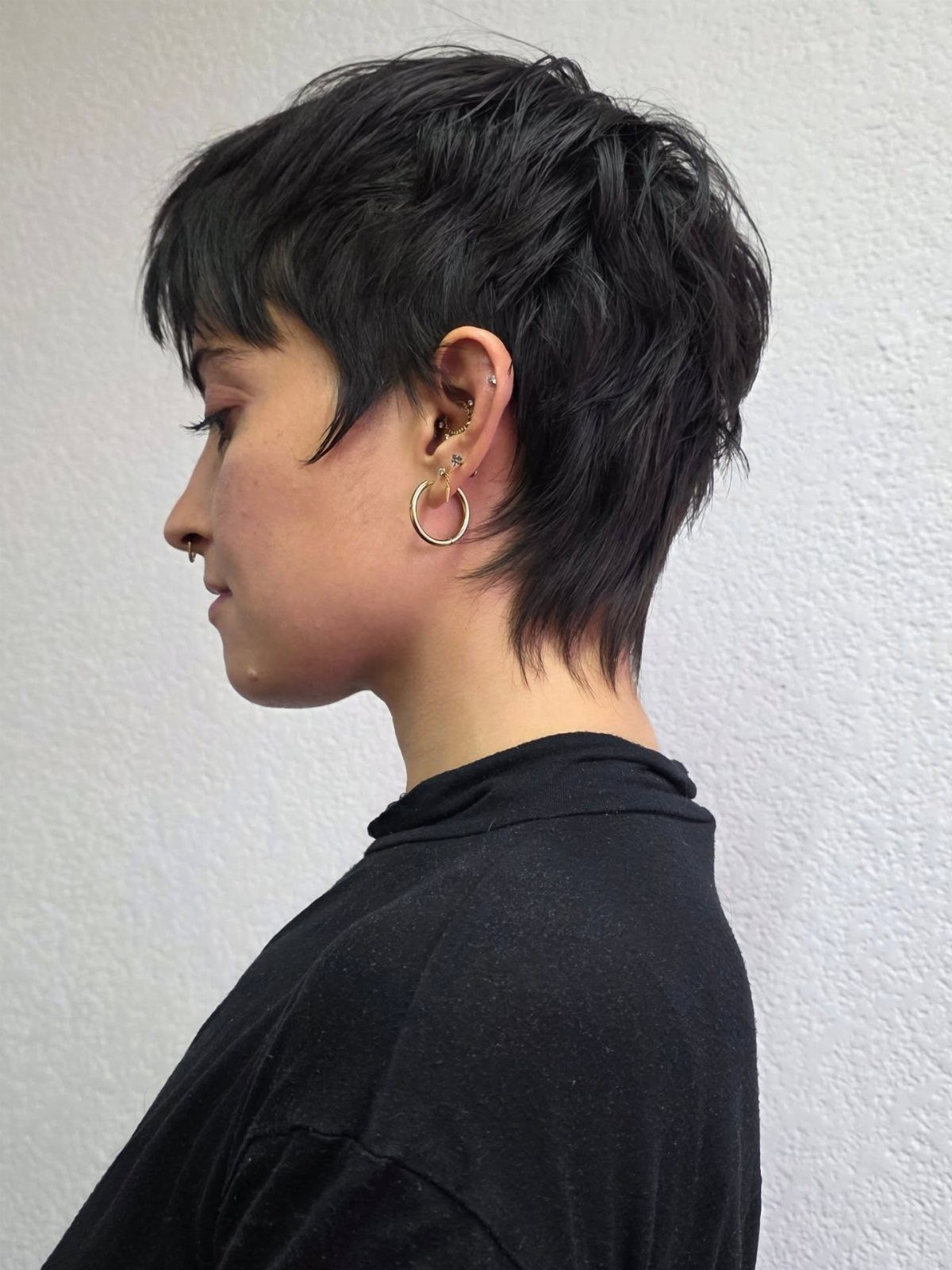 Short layered black pixie cut with bangs shown in side profile