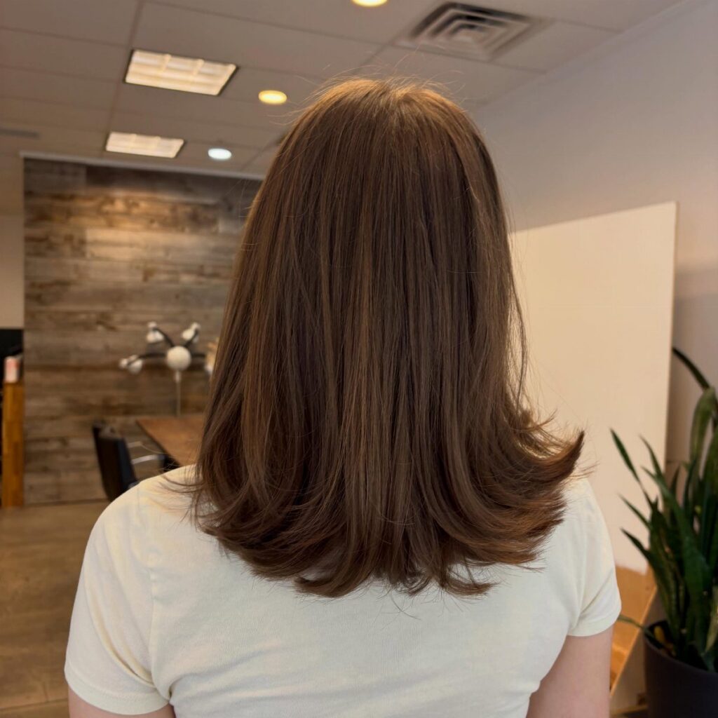 Shoulder-length brown layered hair with softly flipped ends in a salon
