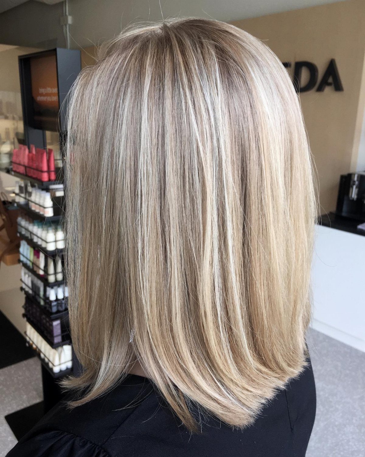 Straight blonde shoulder-length bob with darker lowlights in a salon